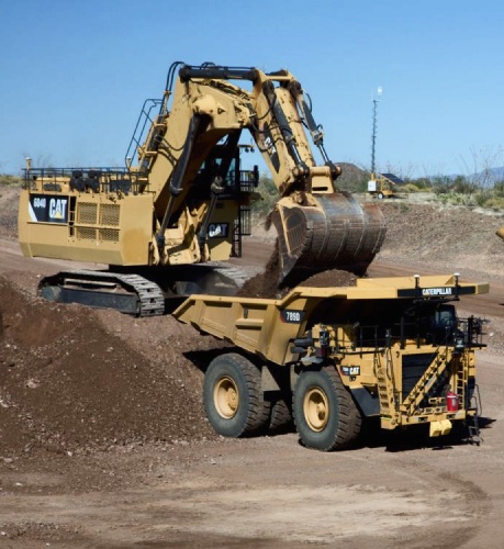 A photo provided by Caterpillar of a bulldozer dumping earth substances in a dump truck.